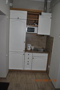 a small kitchen with white cabinets and a sink at Pokoje z łazienkami in Kołobrzeg