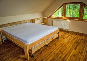 a bedroom with a bed in a room with wooden floors at Viesu māja ar saunu "Lankalni" in Dzelda