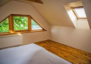 an attic room with a bed and two windows at Viesu māja ar saunu "Lankalni" in Dzelda