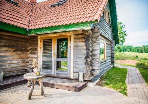 a porch of a log cabin with a table and a window at Viesu māja ar saunu "Lankalni" in Dzelda