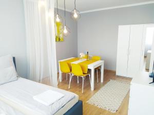 a bedroom with a dining room table and yellow chairs at Lora Apartman in Nyíregyháza +6 photos