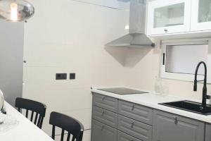 a kitchen with a sink and a counter with chairs at Apartamento tranquilo in Ponferrada