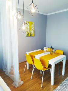 a dining room with a table and yellow chairs at Lora Apartman in Nyíregyháza