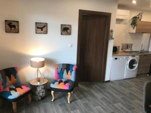 a living room with two chairs and a kitchen at Auberge du Parc in Marckolsheim