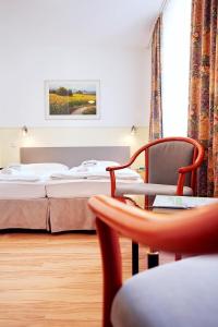 ヴィースバーデンにあるRing Hotelのベッド、椅子、テーブルが備わるホテルルームです。