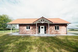 una casa de ladrillo con una puerta blanca en un patio en Ferienhaus Loheide - mit Sauna, en Langenhorn