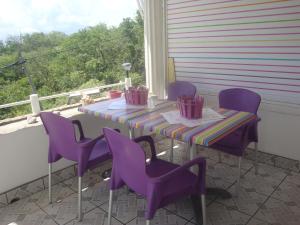 une table et des chaises violettes sur une terrasse couverte dans l'établissement ESCALE CREOLE, à Terre-de-Haut