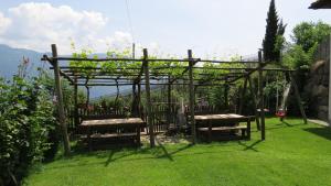 un giardino con pergolato e panchine in erba di Appartements Kirchtalhof a Lana