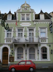 een rode auto geparkeerd voor een groen gebouw bij Hotel Prinz Eitel in Bad Ems