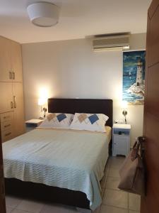 a bedroom with a bed and two tables and a painting at cozy apartment nafpaktos in Nafpaktos