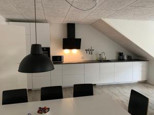 a kitchen with white cabinets and a table with chairs at Lokk-Inn Apartments in Norðdepil