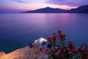 a table and chairs on the edge of a body of water at Hotel Villa Mahal in Kalkan