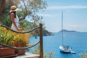 a woman in a hat looking at a boat in the water at Hotel Villa Mahal in Kalkan