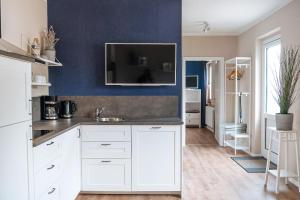 a kitchen with white cabinets and a blue wall at Apartments Am Erdbeerhof in Rövershagen