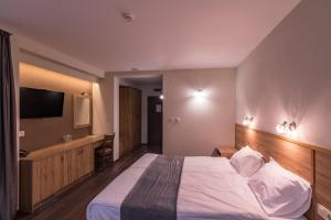 um quarto de hotel com uma cama e uma televisão em Семеен хотел Магнолия em Kazanlŭk