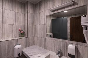 uma casa de banho com um lavatório e uma televisão na parede em Семеен хотел Магнолия em Kazanlŭk