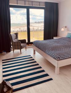 a bedroom with a bed and a chair and a window at Apartament Błękitny przy Latarni in Darłowo