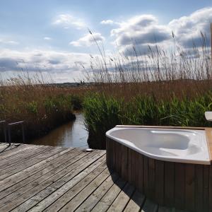 a bath tub sitting on a wooden deck next to a river at Pfahlbau Rust/Neusiedlersee Sunset I in Rust