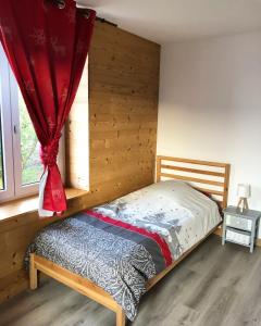 a bedroom with a bed with a red curtain at Chez Léa et Lolo - Le Nordique in Gérardmer