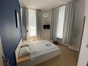a bedroom with a bed and two windows at Apartamenty Stare Miasto in Bydgoszcz