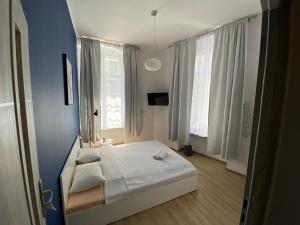 a bedroom with a white bed and a blue wall at Apartamenty Stare Miasto in Bydgoszcz