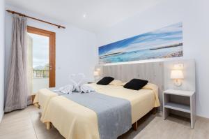 two beds in a room with a painting on the wall at Venecia Apartments in Port d'Alcudia +98 photos