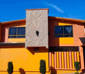 une maison jaune et orange avec un mur dans l'établissement Hospedaje Ensueño, à Zacatlán