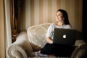 a woman sitting on a chair with a laptop at Hotel Resort&Spa Kamelot in Kamenitsa
