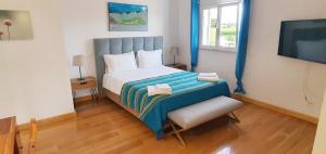 a small bedroom with a bed and a television at Sunset Villa by Laranjal Rentals in Olhos de Água