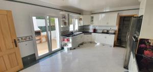 a kitchen with white cabinets and a large window at Sunset Villa by Laranjal Rentals in Olhos de Água