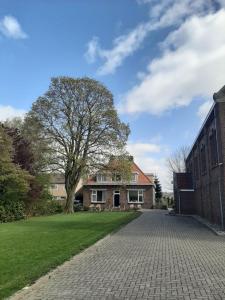 una casa con un árbol en medio de una entrada en De Herberg, en Elim