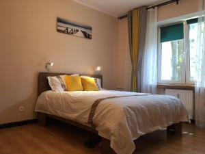 um quarto com uma cama com almofadas amarelas e uma janela em Travel Apartment em Varsóvia