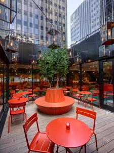 um pátio com mesas e cadeiras vermelhas e uma árvore em citizenM Paris Gare de Lyon em Paris