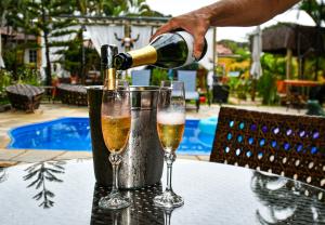 a person pouring champagne into two glasses on a table at Relais Amadeus Pousada de Charme in Pirenópolis