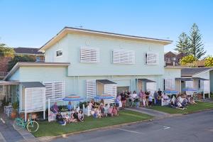 un groupe de personnes assises devant une maison dans l'établissement La Costa Beachside Motel, à Gold Coast