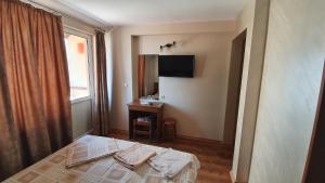een slaapkamer met een bed, een bureau en een raam bij Family Hotel The Rocks in Belogradchik