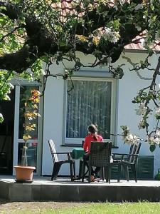 a woman sitting at a table in front of a building at FEWO-ATLANTA Reinhardshausen in Reinhardshausen