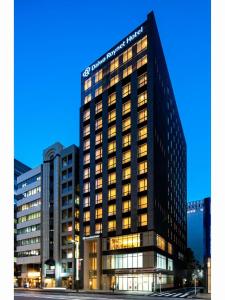 Daiwa Roynet Hotel Tokyo Kyobashi PREMIER في طوكيو: مبنى طويل وبه العديد من النوافذ في الليل