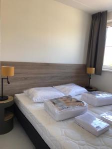 two twin beds in a bedroom with two lamps at de Putter in Hollum