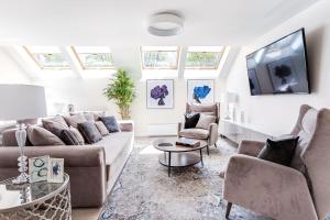 uma sala de estar com um sofá e cadeiras e uma televisão em Luxury for everyone - Hills Park Lux Apartments 1 em Vilnius