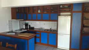 La cuisine est équipée de placards bleus et d'un réfrigérateur blanc. dans l'établissement Periyali, à Keratea