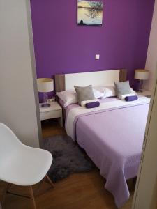 um quarto roxo com 2 camas e uma cadeira em Tomena apartments em Trogir