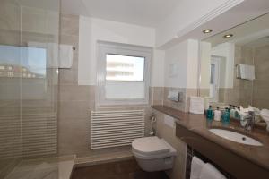 een badkamer met een toilet, een wastafel en een douche bij Hotel Wiking Sylt in Westerland