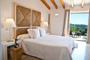 a bedroom with a bed and a large window at Cases de Son Barbassa Hotel & Restaurant in Capdepera