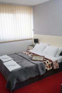 um quarto com uma cama grande e almofadas brancas em Rooms S&S Milicevic u strogom centru Aleksandrovca em Aleksandrovac