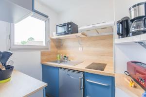 a small kitchen with blue cabinets and a sink at Le coeur de Royan studio 2 étoiles in Royan