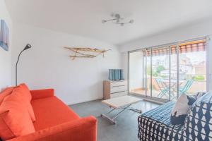 sala de estar con sofá naranja y ventana en Le coeur de Royan studio 2 étoiles, en Royan