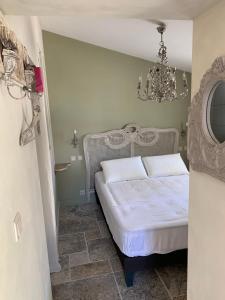 - une chambre avec un lit blanc et un lustre dans l'établissement La Rochelle L'ile de Ré Autrement, à Nieul-sur-Mer