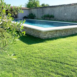 una piscina in un cortile con un muro di pietra di La Rochelle L'ile de Ré Autrement a Nieul-sur-Mer