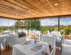 a restaurant with white tables and chairs and windows at Cases de Son Barbassa Hotel & Restaurant in Capdepera